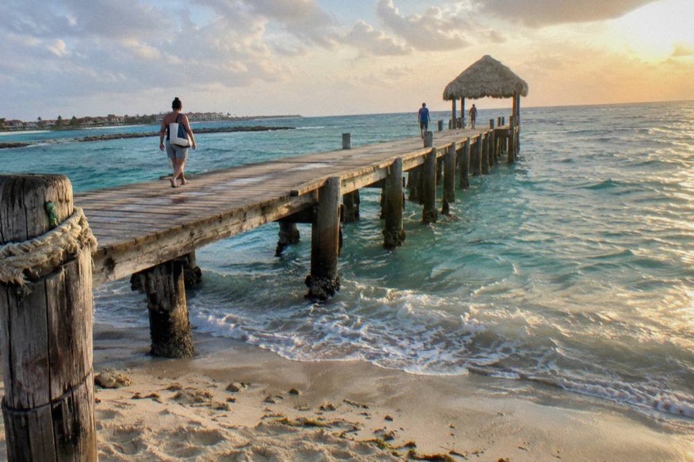 Long wooden pier extending into calm turquoise water in golden evening light