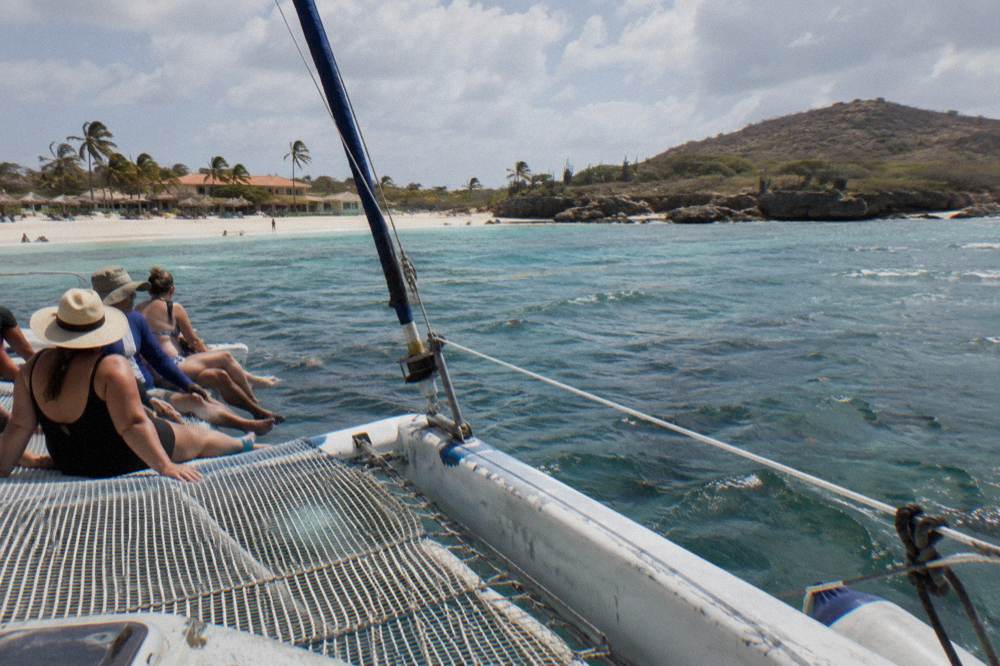 Group of guests seated along the netting of a catamaran in warm late afternoon light