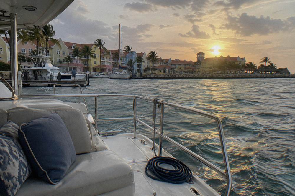 An evening boat deck with cushions and railings as the sun sets over open water in warm light