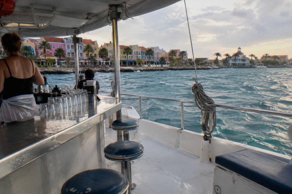 Open deck of a catamaran with drinks on the bar counter and calm turquoise sea beyond the rail