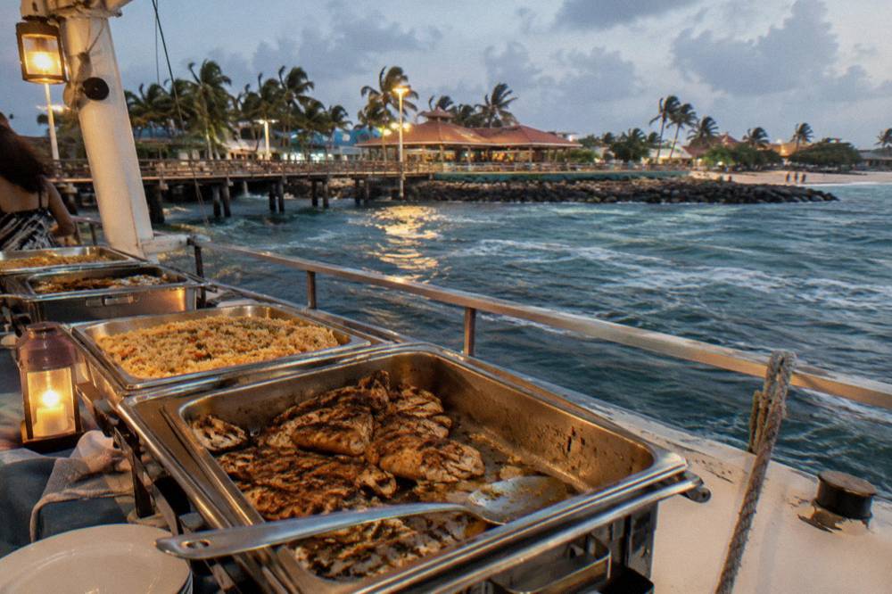 Evening buffet dinner set out on a boat deck with warm lantern light