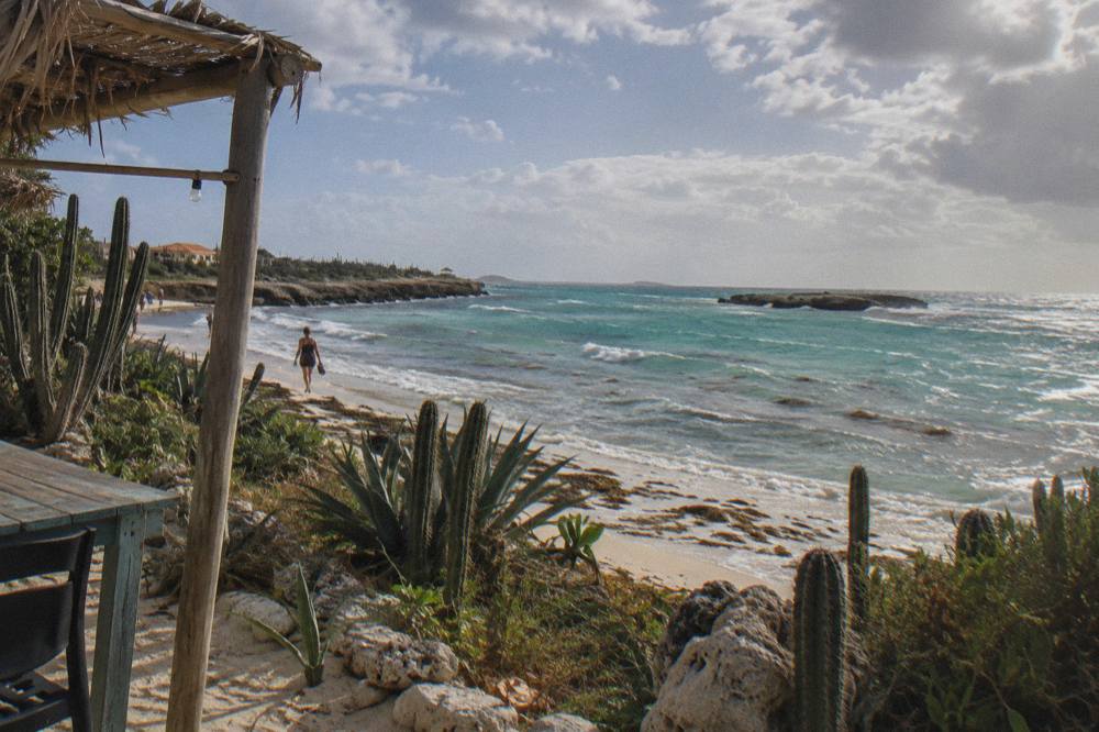 Sunlight breaking through parted clouds over turquoise sea along an arid coastline