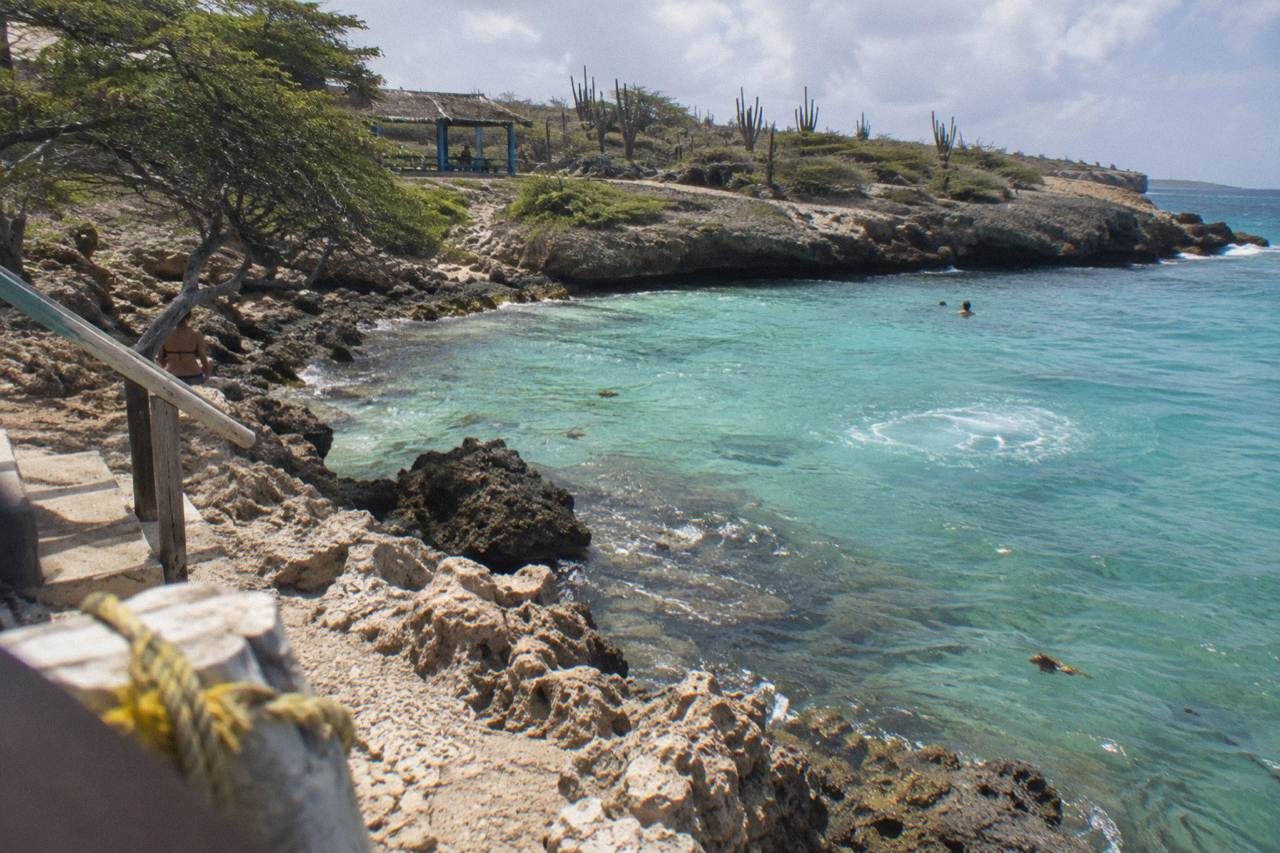 Clear shallow turquoise water over a rocky shoreline in Aruba at late afternoon