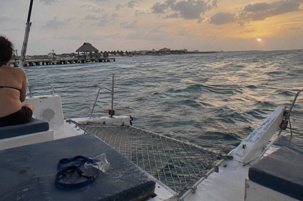 Open-air catamaran deck with seating and a calm sea at dusk