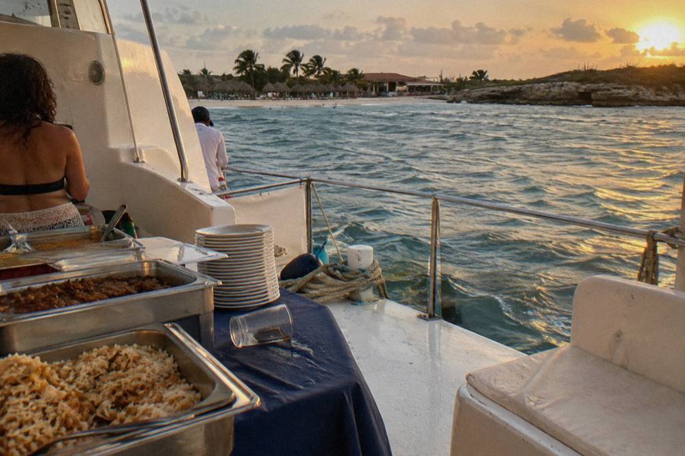 Dinner table set on a boat deck with plates and glasses at sunset