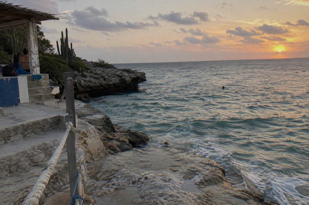 Warm pink and gold sky above still water after sunset near Aruba