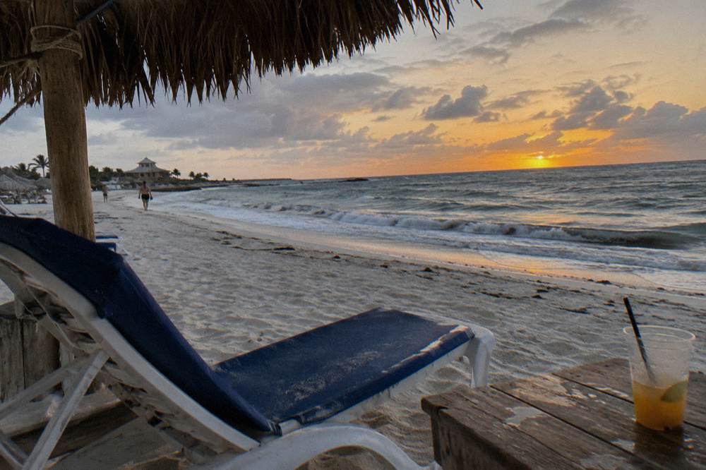 Sun chair and empty beach at twilight with a deep orange band fading along the horizon