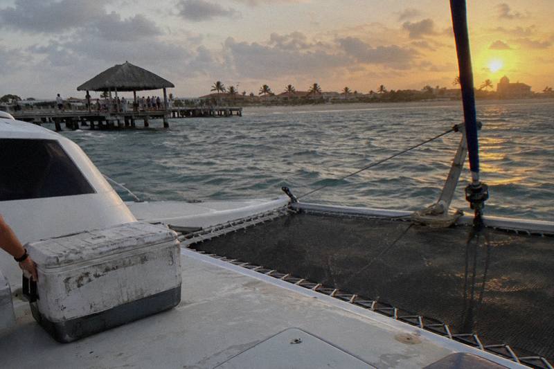 White sailing catamaran under sail off Aruba at golden hour