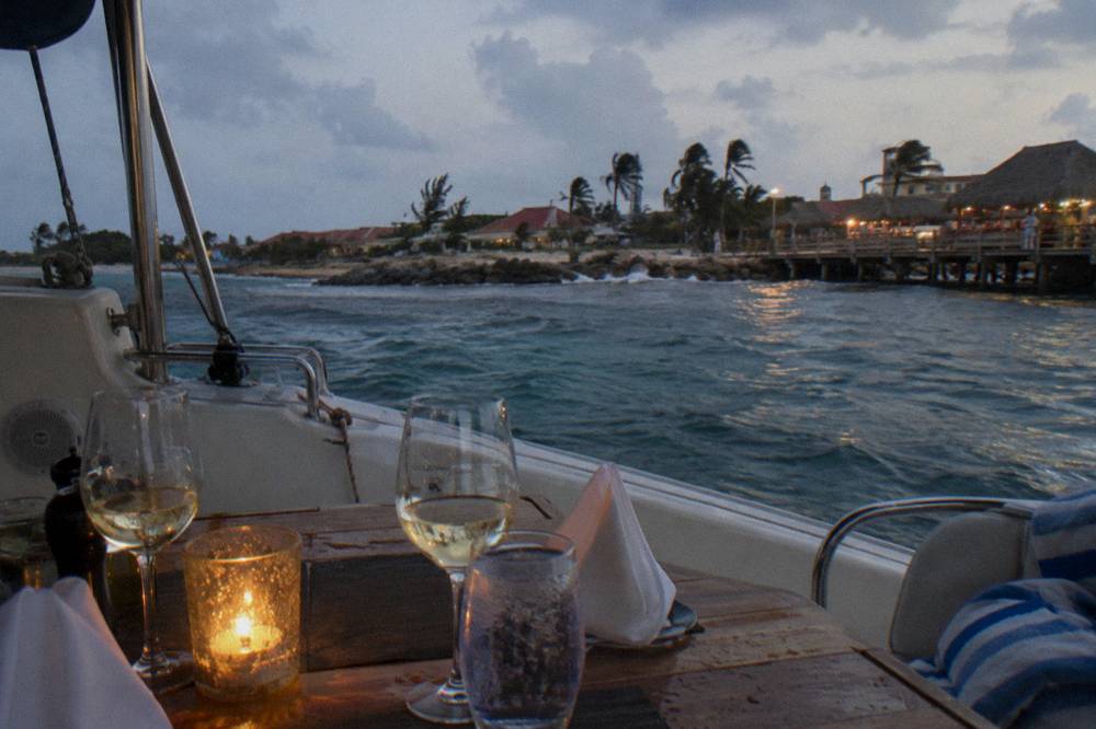 Dinner table set on a boat deck with wine glasses at dusk