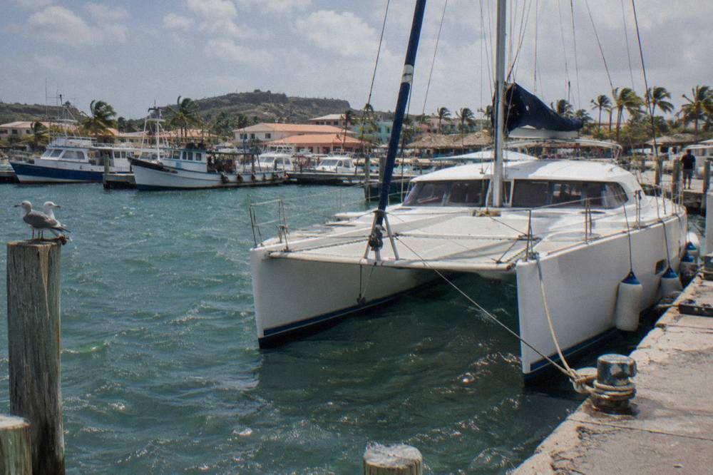 A private catamaran moored at a marina in Oranjestad with calm water and moored boats nearby