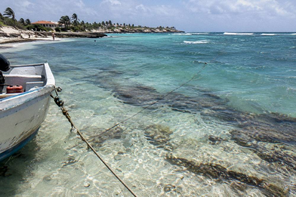Clear shallow water over a coral and rock seabed along the Aruba coastline near a boat anchor