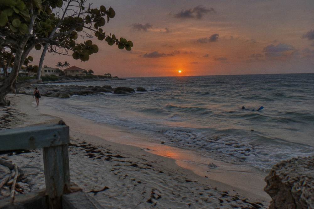 Deep orange sun touching the horizon over the Caribbean with darkening sky and gentle waves