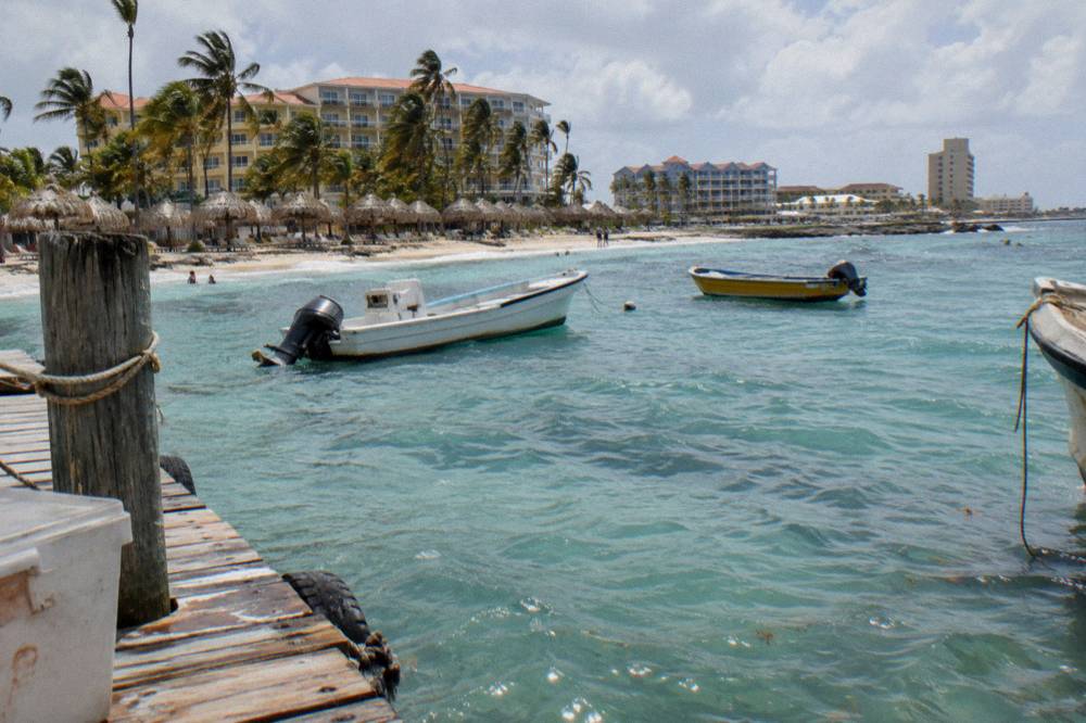Wooden pier on Palm Beach in late afternoon with calm turquoise water and boats at rest