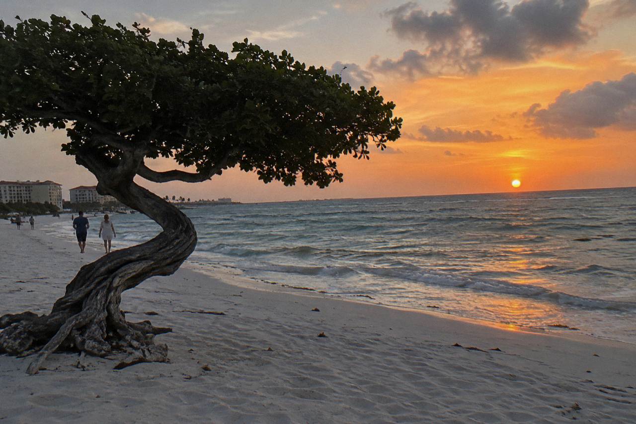 Sun sinking into the Caribbean Sea off the Aruba coast with calm water and a deep orange sky
