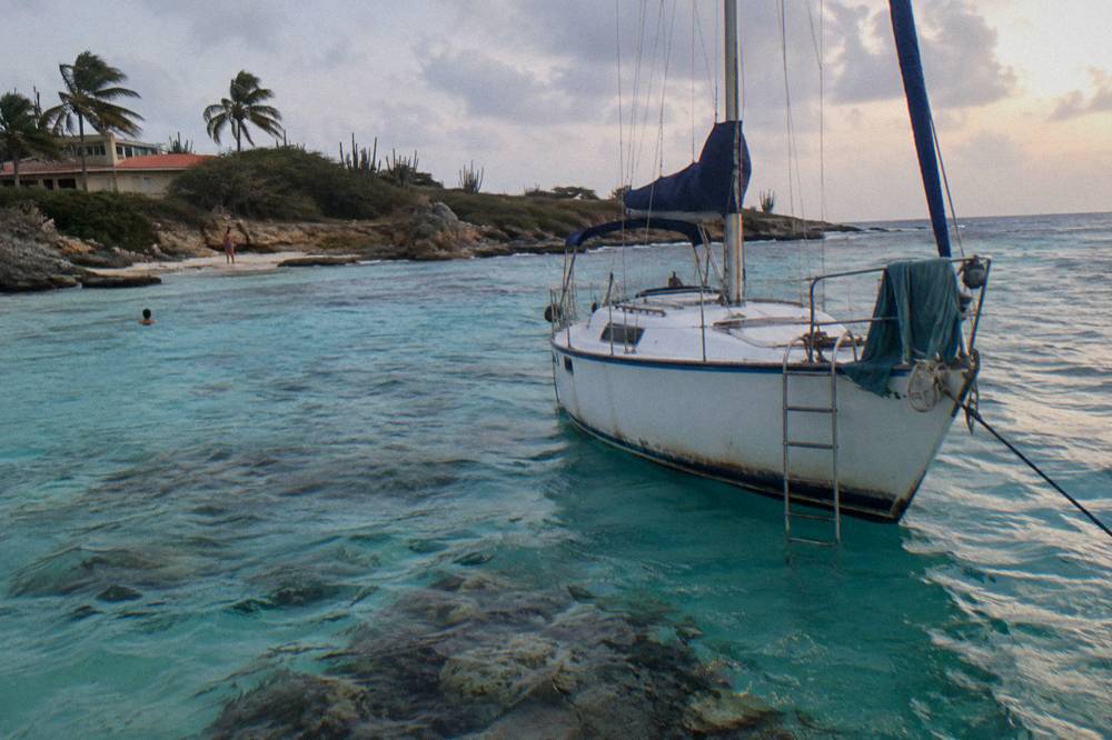 A small boat anchored over clear shallow water above a reef at dusk