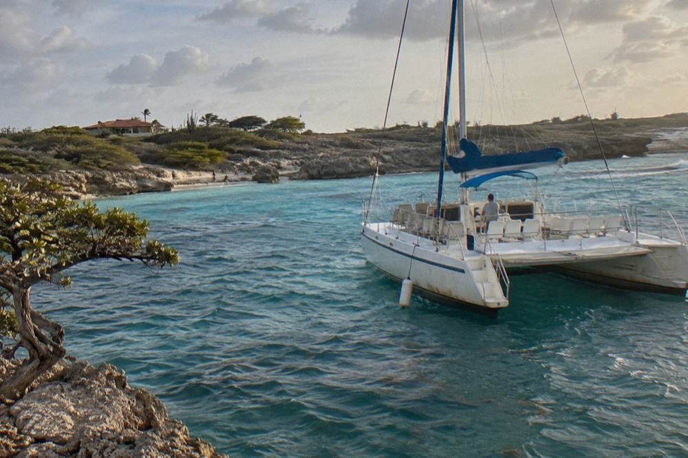 Private catamaran anchored in quiet bay with empty deck seats in warm evening light