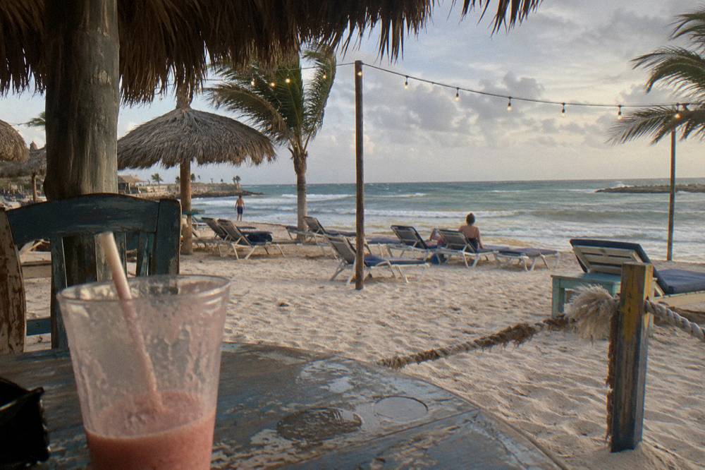 Open air beachside bar with string lights and empty deck chairs before sunset