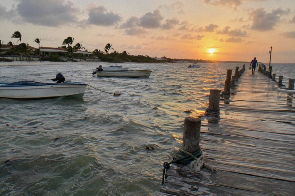 Long wooden pier extending over calm water toward the setting sun