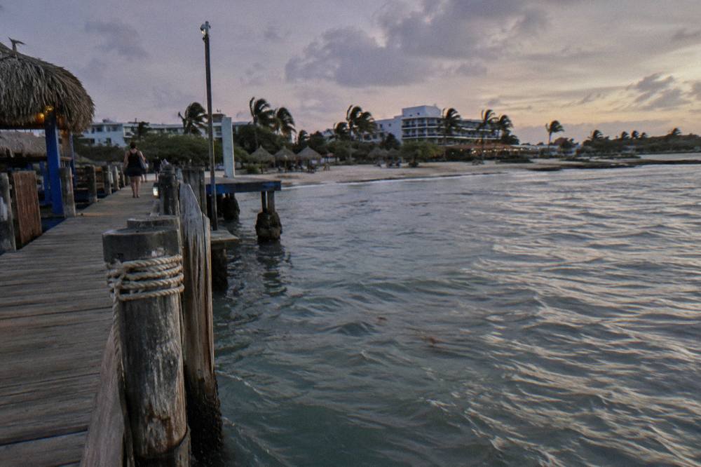 A wooden pier extending over calm Caribbean water at dusk