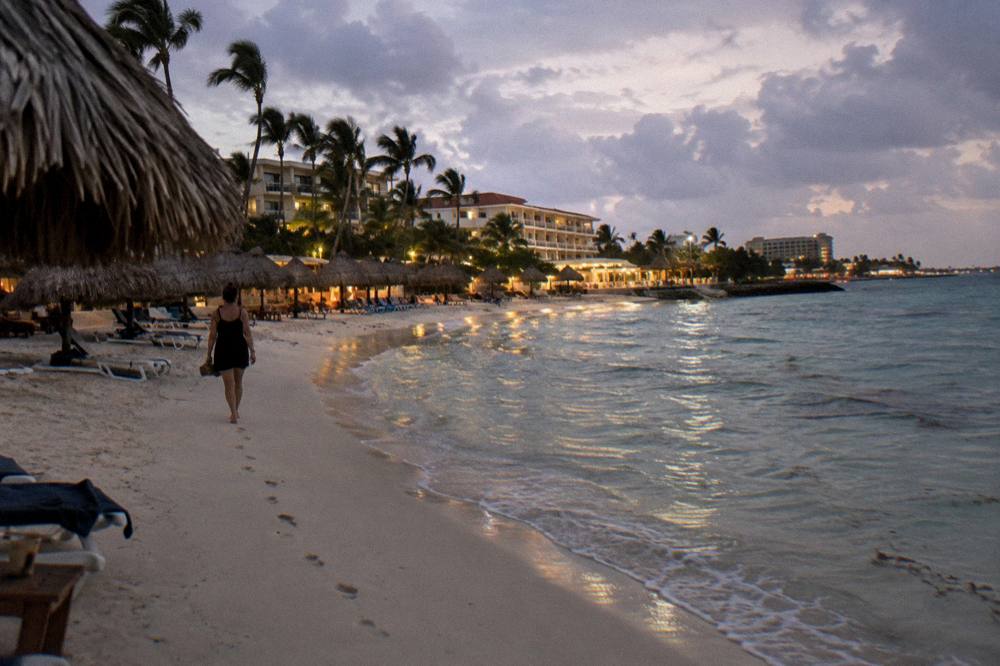 Beachfront resorts lit at dusk along a calm Caribbean shoreline