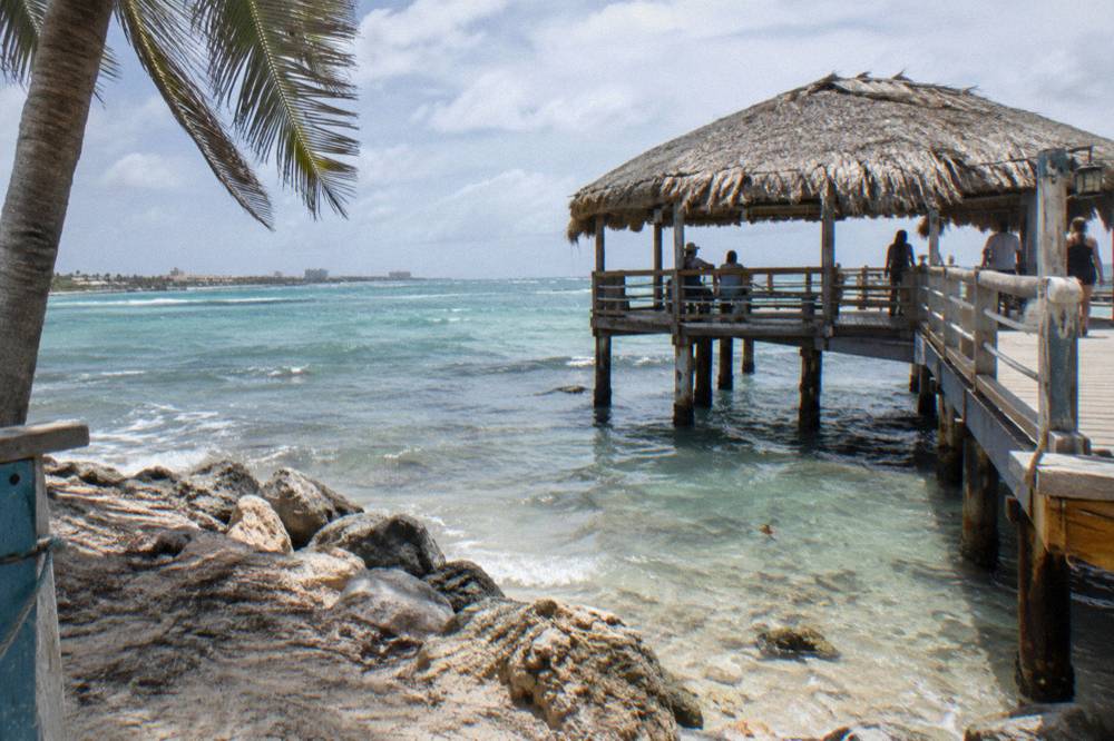 Wooden pier with thatched shade structure above clear shallow water