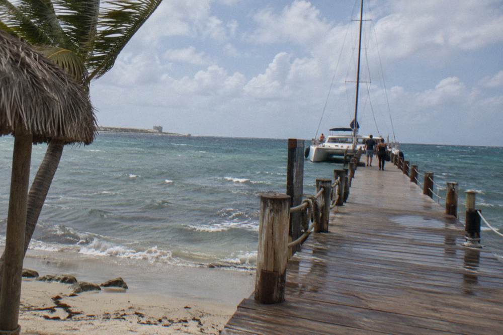 Long pier reaching from a beach into open water under a partly cloudy sky