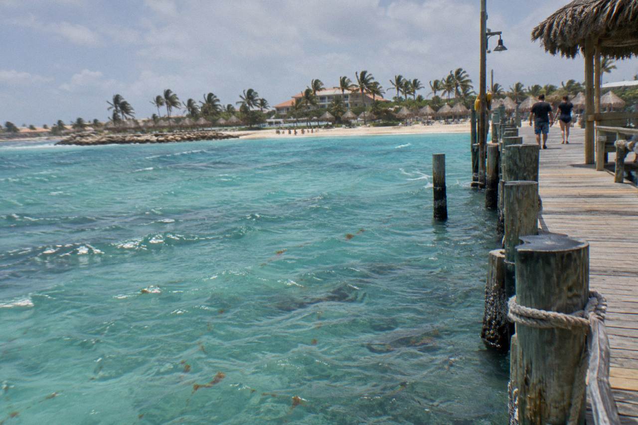 Weathered wooden pier extending over calm turquoise water toward a low horizon