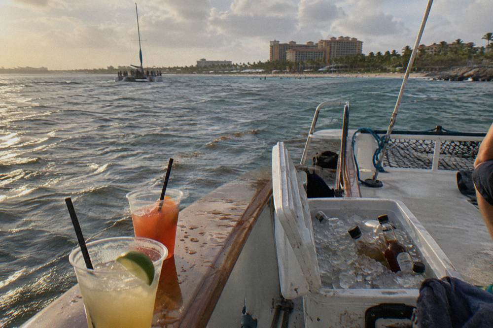 Cocktail glasses and a cooler of drinks on a boat deck rail in warm evening light