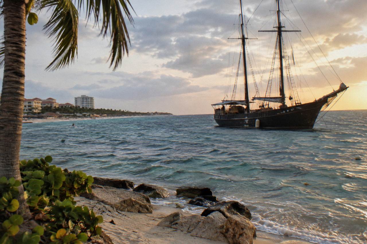 Pirate style schooner with tall masts anchored off Palm Beach at golden hour