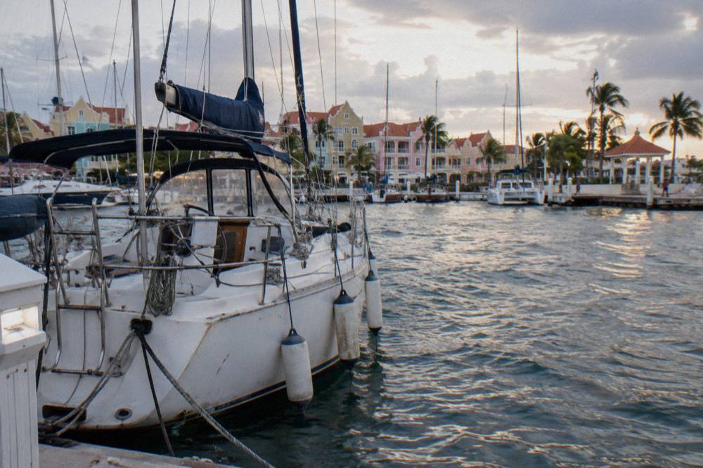 A private sailing boat moored at a marina in Oranjestad with calm evening water and moored masts