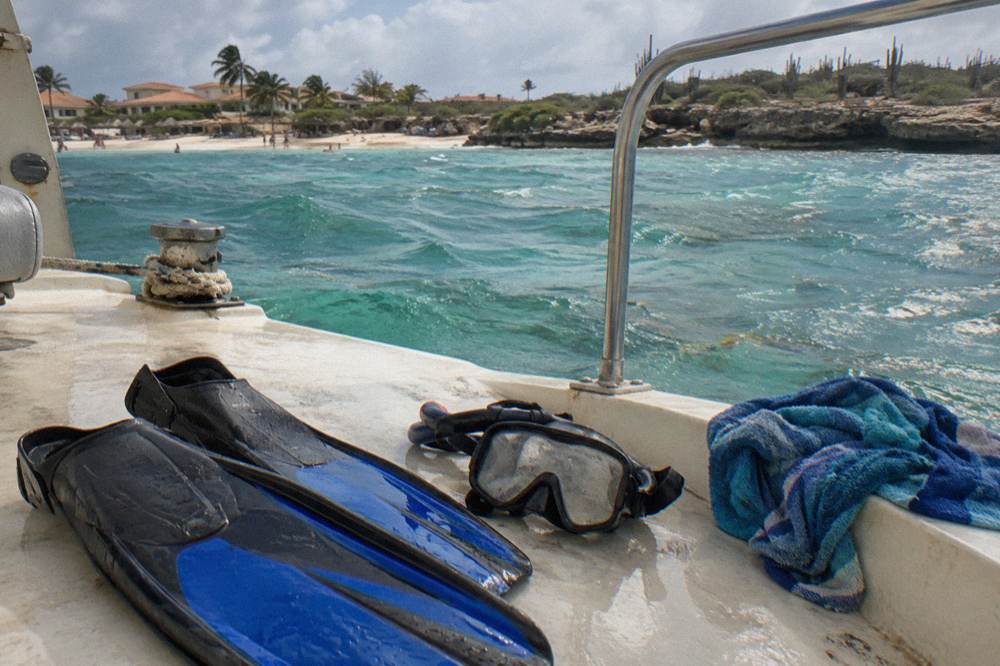 Snorkel fins and a mask arranged on the deck of a small boat in late afternoon light