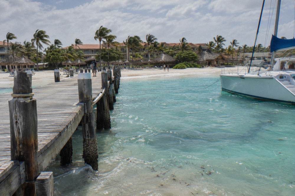 A wooden pier extending from a Palm Beach resort into calm turquoise water
