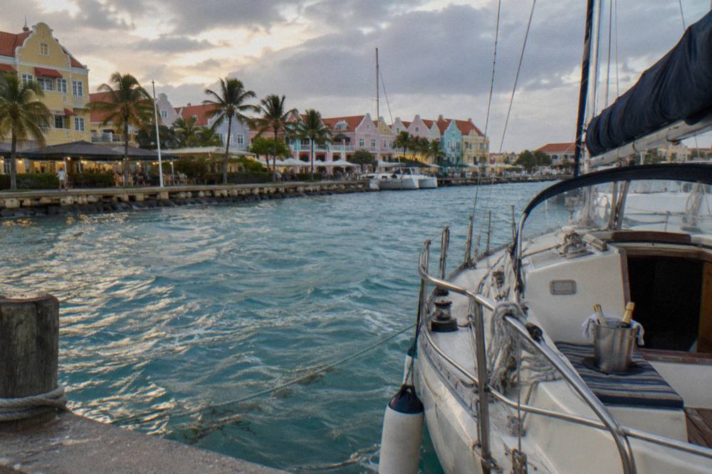 A sailboat moored beside colorful waterfront buildings at dusk