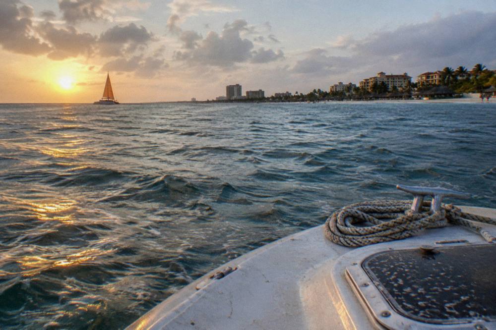 An open boat deck facing west toward a sun low over smooth water near the horizon