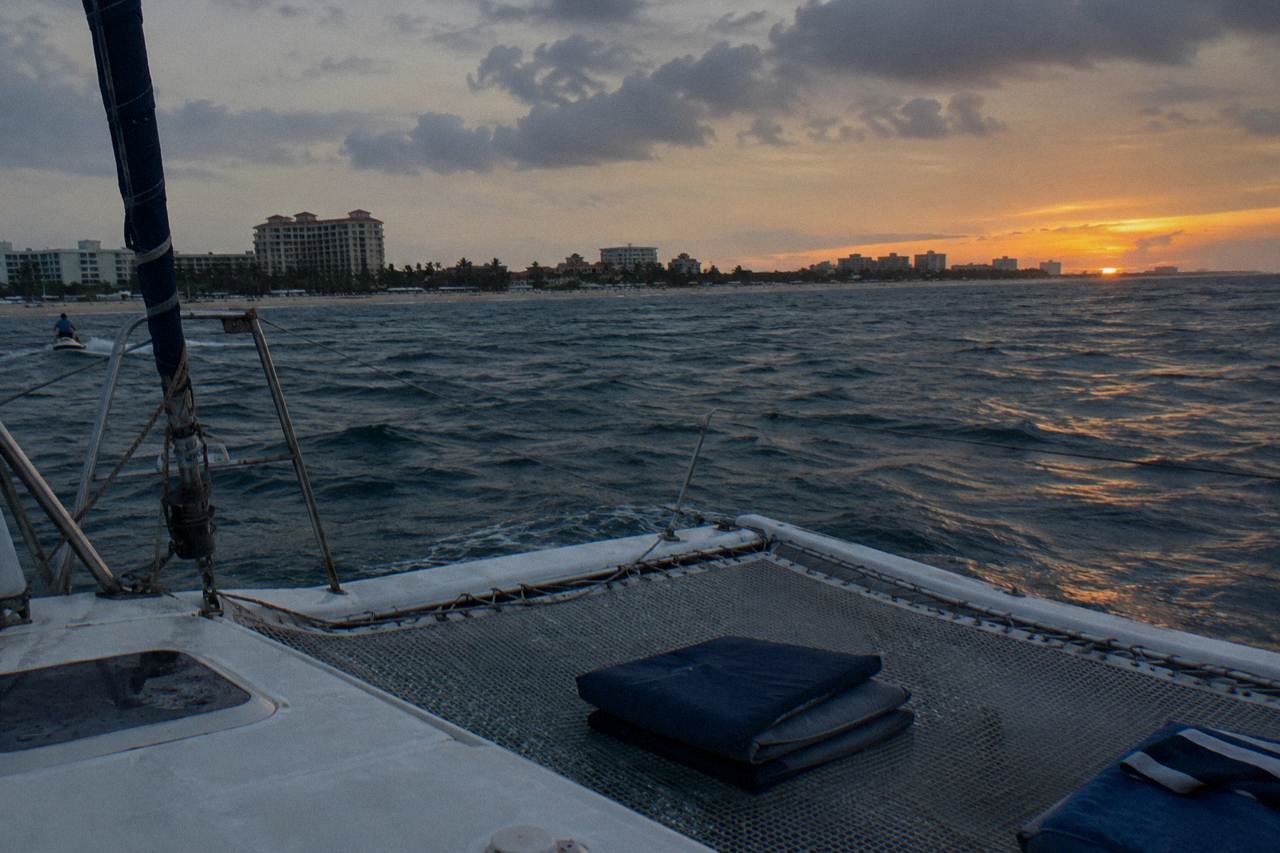 A quiet catamaran deck at dusk with calm sea and a darkening sky over the water