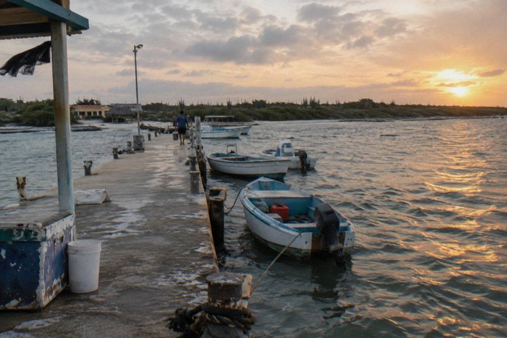 A wooden pier stretching into calm evening water on the sheltered west coast of Aruba