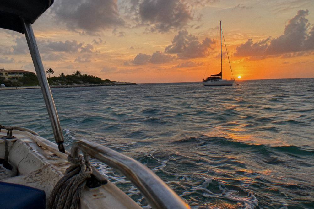An orange sunset over calm sea along the west coast of Aruba seen from the water