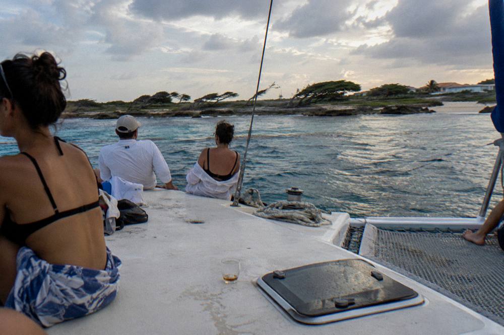 Guests seated midship on a wide catamaran deck during a calm evening sail in Aruba