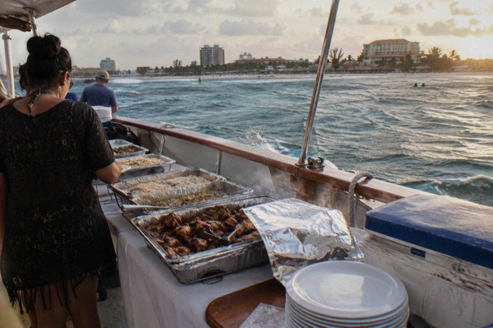 Buffet dinner laid out on a boat deck with serving dishes and warm evening light