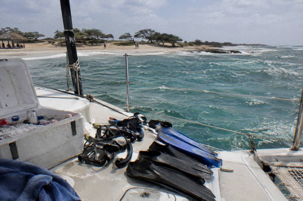Snorkel masks and fins arranged on a boat deck beside a cooler in afternoon light