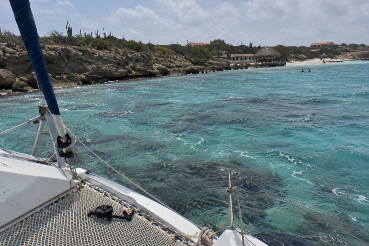Catamaran anchored near a coral reef in calm turquoise water off the Aruban coast at late afternoon