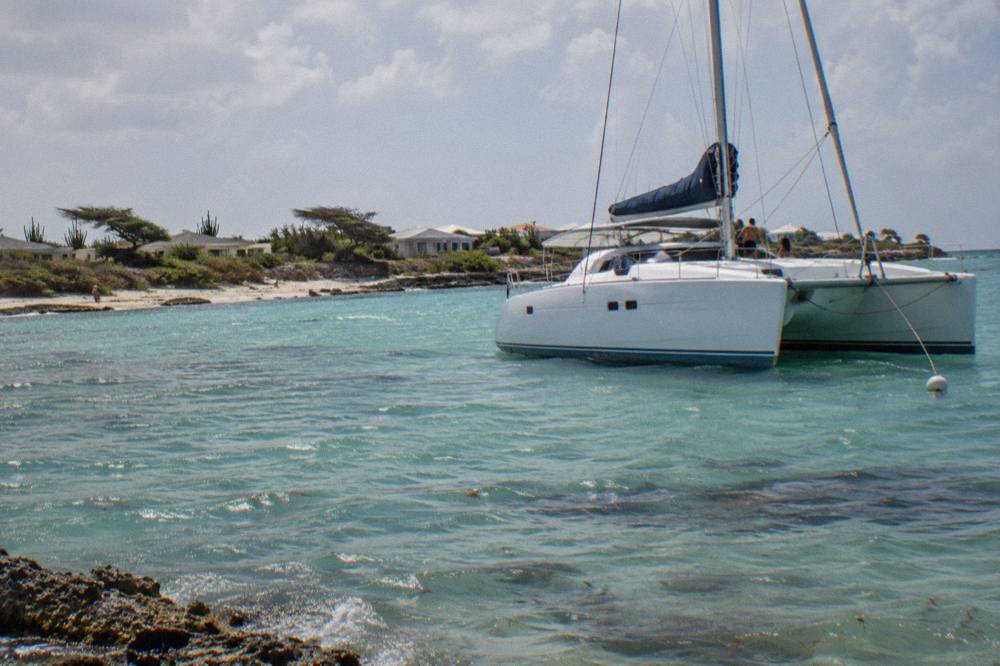 A catamaran anchored in calm turquoise water near a reef on Aruba's northwest coast