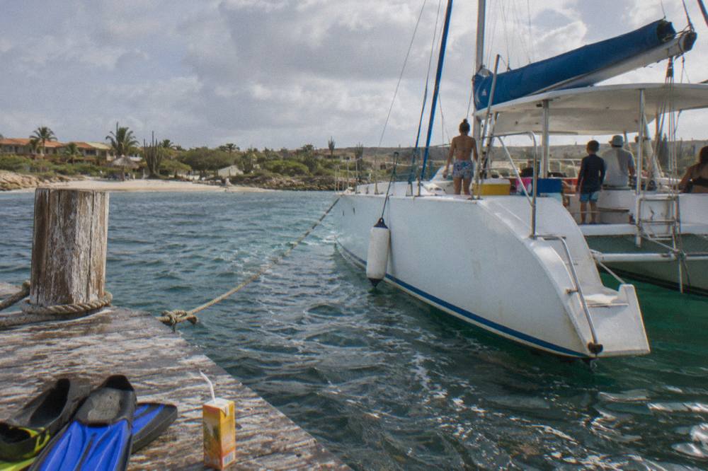 An open-deck catamaran moored at a wooden pier on Palm Beach before departure