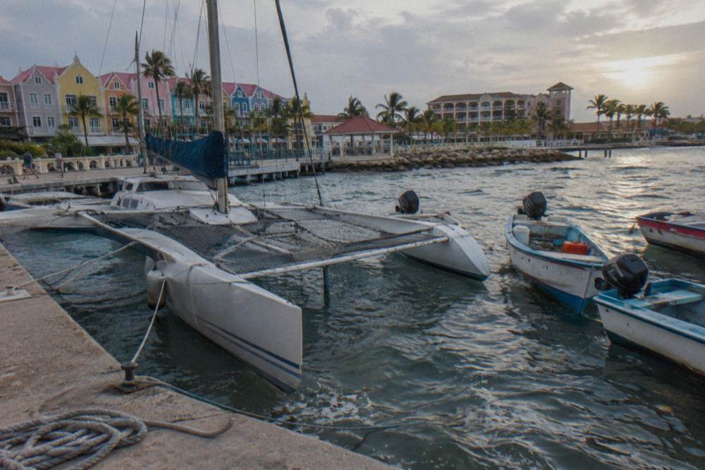 A trimaran and small watercraft on calm water near Oranjestad marina at dusk