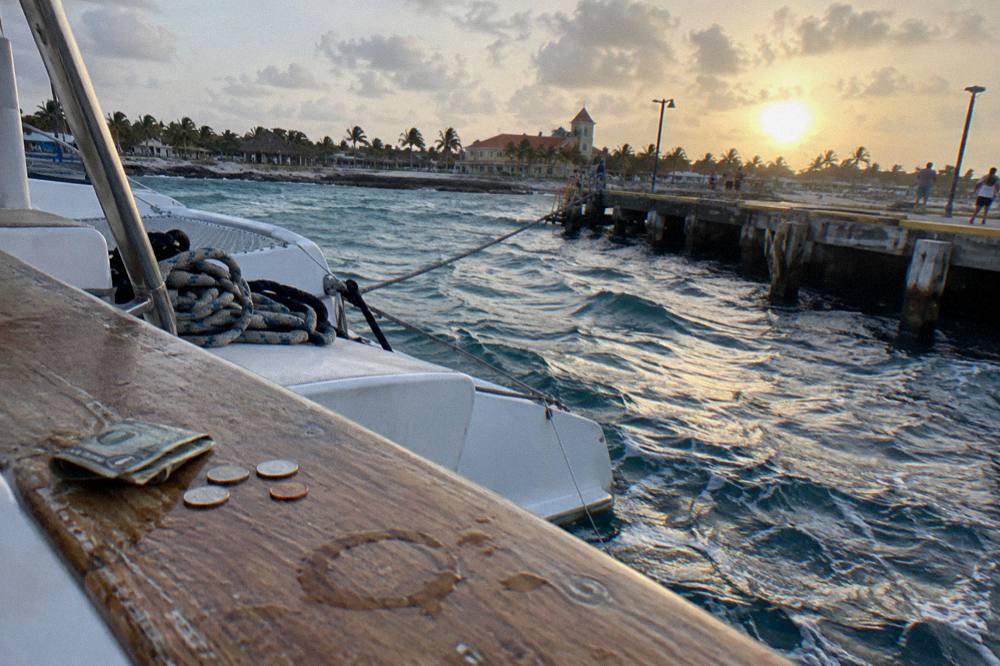 Boat deck rail with a small pile of cash and a sunset over open water