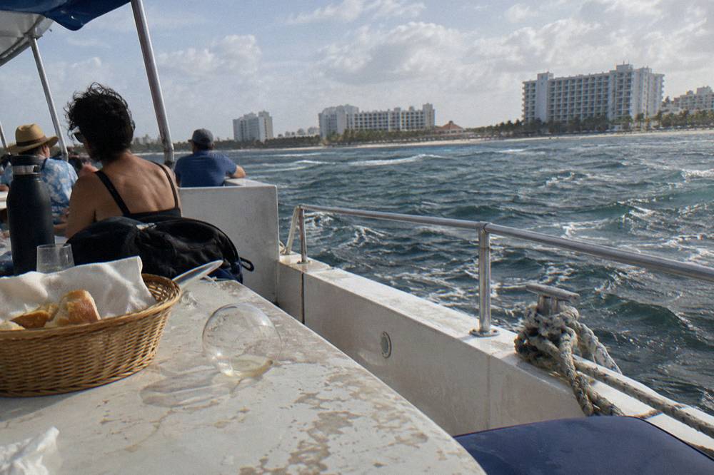 Passengers seated at a dinner table on an open boat deck in late afternoon light